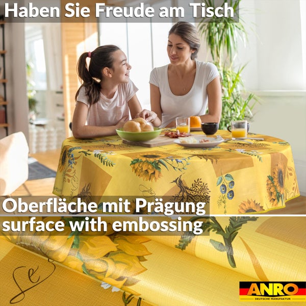 Runde Tischdecke mit Sonnenblumenmuster und geprägter Oberfläche an einem gedeckten Tisch mit zwei Personen. ANRO Logo.