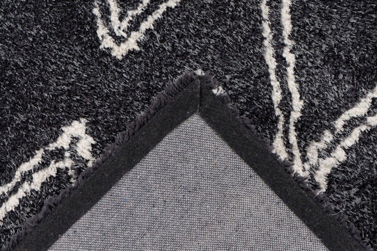 Nahaufnahme eines Hochflor-Teppichs in Anthrazit mit weißem Muster und Ansicht der Textilrückseite.