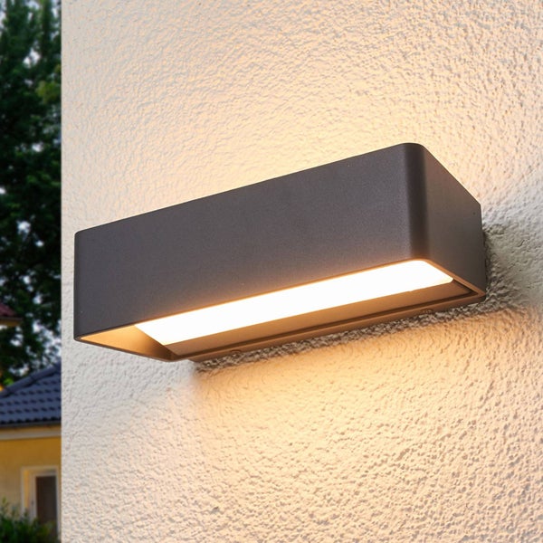 Rechteckige LED-Außenwandleuchte in Anthrazit an einer strukturierten Hauswand mit warmem Lichtaustritt nach oben und unten.