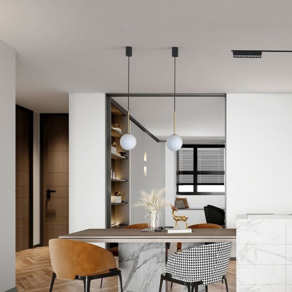Moderne Pendelleuchten mit runden Glasleuchten über einem Esstisch in einem hellen, elegant eingerichteten Wohnbereich mit Parkettboden.