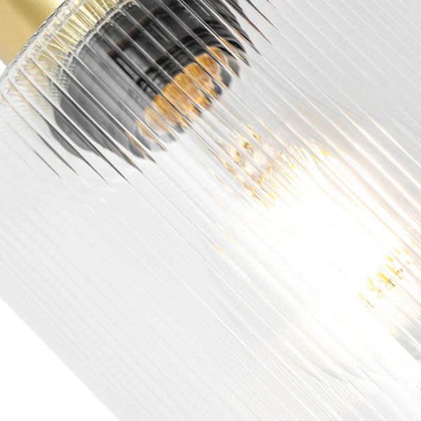 Detailaufnahme einer Lampe mit geripptem Glasschirm und eingeschalteter Glühbirne.