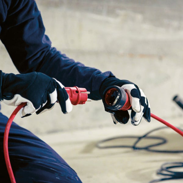 Eine Person verbindet ein rotes Stromkabel mit Stecker und Kupplung