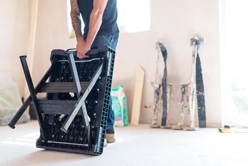 Eine Person trägt eine zusammengeklappte Trittleiter.