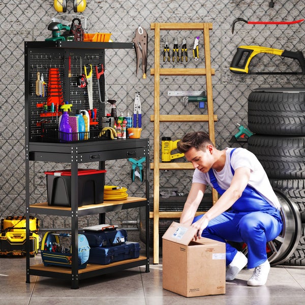 Organisierte Werkstatt mit einer schwarzen Werkbank aus Metall inklusive Lochwand für Werkzeuge und einem Mann in blauen Arbeitshosen.