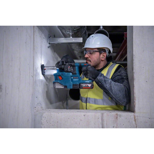 Ein Bauarbeiter bohrt mit einem Akku-Bohrhammer ein Loch in eine Betonwand.