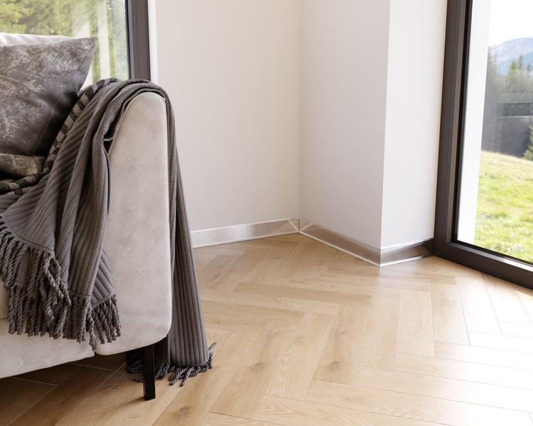 Szene mit Sockelleisten, hellem Parkettboden und Teil eines Sofas