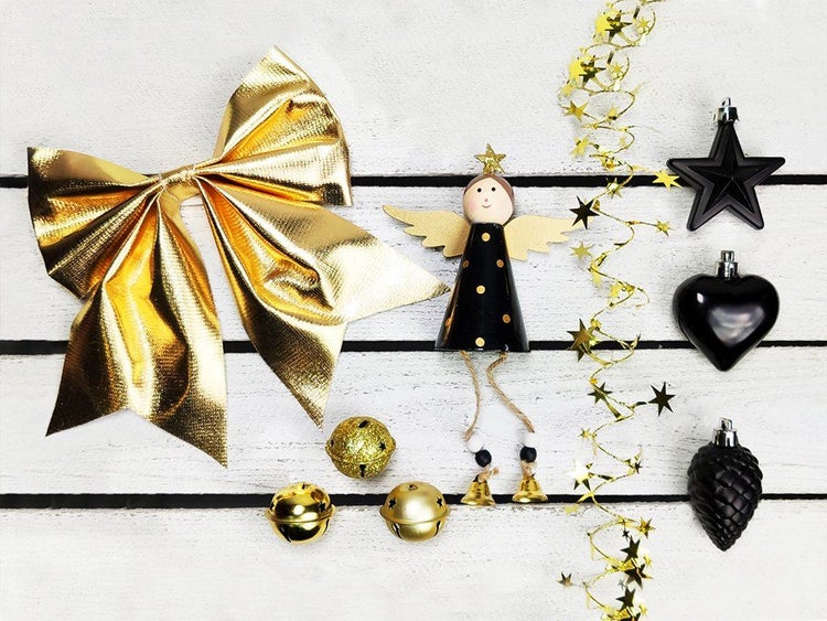 Weihnachtsdekoration Set mit einer Engelsfigur, Schleife, Sternen, Weihnachtskugeln und Glocken auf weißem Holzuntergrund.