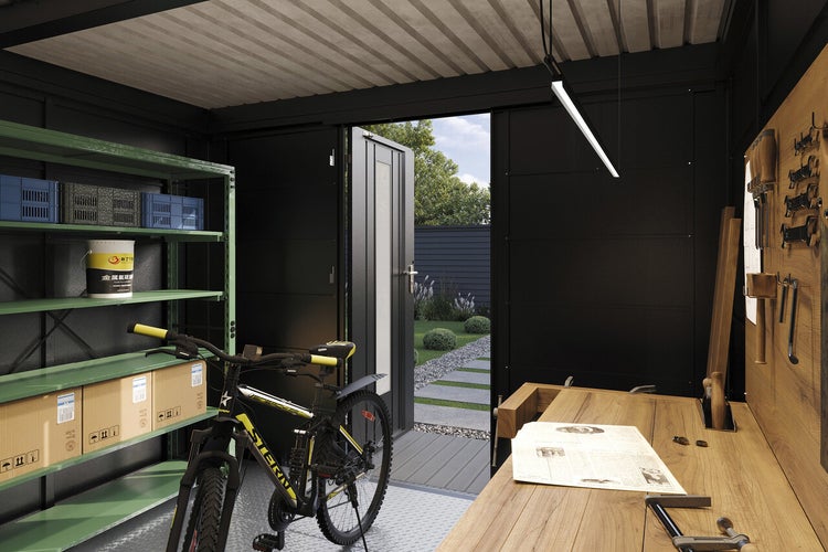 Moderne Gartenwerkstatt mit Werkbank aus Holz, Metallregal, Fahrrad und Blick in den Garten durch die geöffnete Tür.