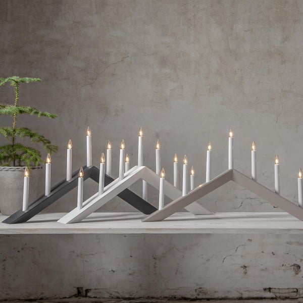 Drei unterschiedlich gefärbte Adventsleuchter mit elektrischen Kerzen auf einem Sims.