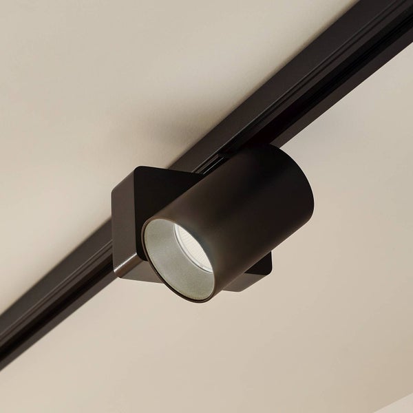 Schwarzer Strahler für Schienensysteme in zylindrischer Form an einer schwarzen Stromschiene montiert.
