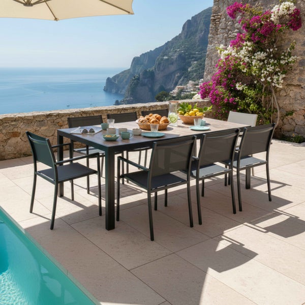 Gelbes Gartenmöbel-Set aus Metall mit quadratischem Tisch und vier Stühlen auf einer Holzterrasse vor grünem Hintergrund.