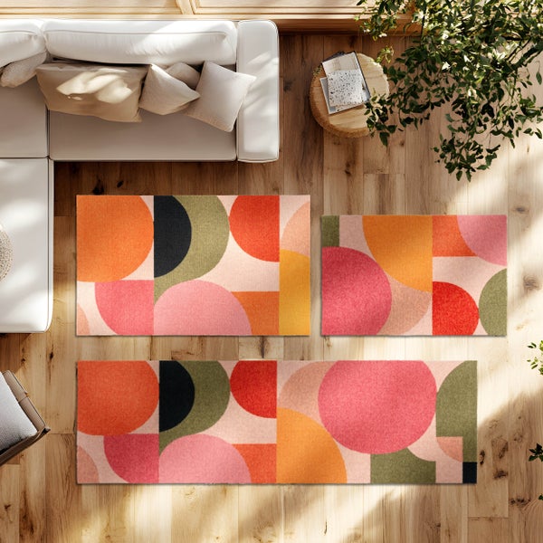 Geometrisch gemusterte Teppiche auf Holzfußboden in einem hellen Wohnzimmer mit weißem Sofa in der Draufsicht.