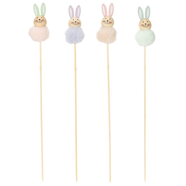 Dekorative Hasenfiguren aus Holz und Plüsch auf Holzstäben, als Osterdekoration.