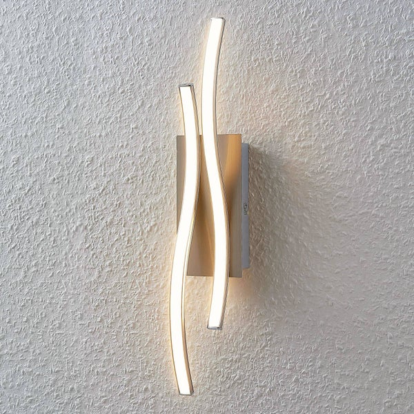Moderne LED-Wandleuchte in Wellenform aus Metall mit zwei geschwungenen Lichtstreifen an einer strukturierten Wand.