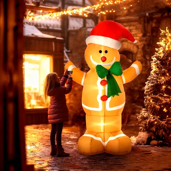 Großer aufblasbarer Lebkuchenmann mit integrierter Beleuchtung, Weihnachtsmütze und Schleife in einer weihnachtlichen Außenszene mit Kind.