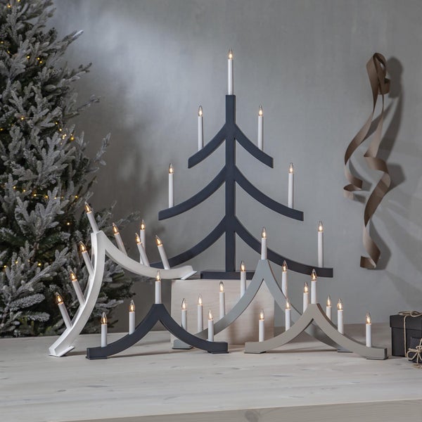 Dekorative elektrische Schwibbögen und ein Baum aus Holz mit Kerzenleuchten für die Weihnachtszeit.