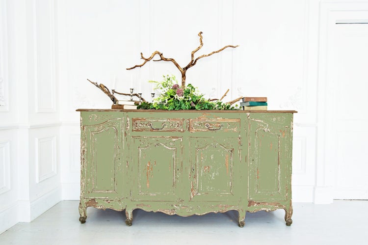 Antike grüne Kommode mit Holzdekoration, Kerzenständern und Büchern in hellem Raum