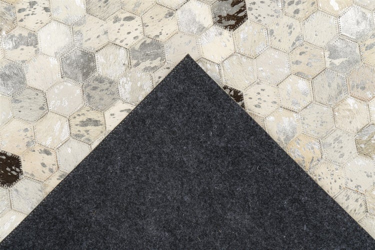 Patchwork-Teppich mit sechseckigen Feldern in Felloptik, silbernen Akzenten und einer dunklen Filzrückseite.