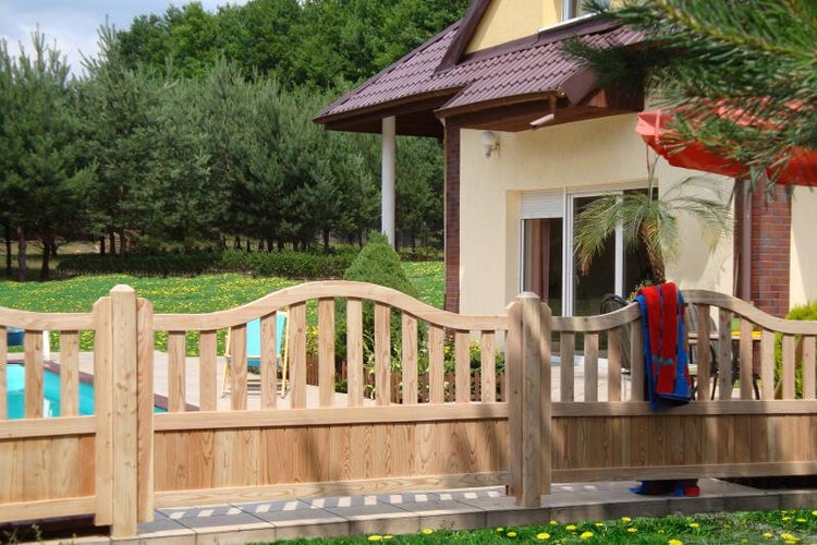 Holzzaun mit geschwungenem Design vor einem Haus