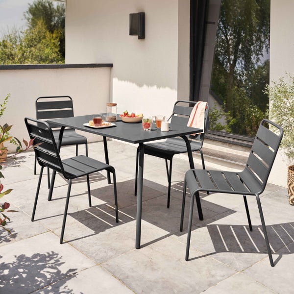 Modernes Gartenmöbel-Set aus Metall in Anthrazit mit einem rechteckigen Tisch und vier Stapelstühlen auf einer hellen Steinterrasse.