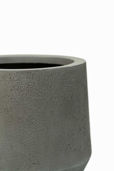 Detail eines runden Pflanzgefäßes mit strukturierter Oberfläche in Betonoptik.
