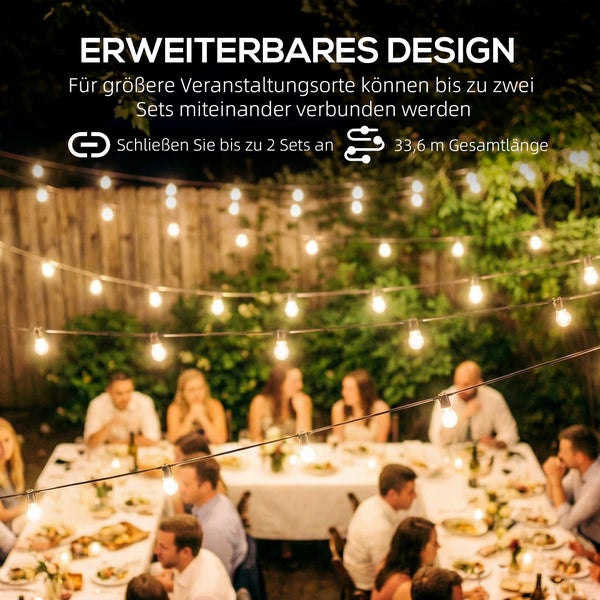 Gartenparty bei Nacht mit Personen an einem Tisch unter einer erweiterbaren Lichterkette. Gesamtlänge bis zu 33,6 Meter.