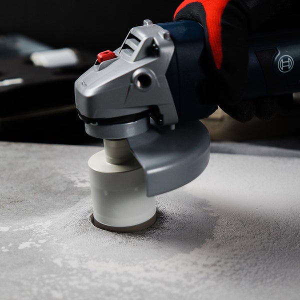 Winkelschleifer beim Bohren eines Lochs in eine Betonplatte mit einem Bohrwerkzeug