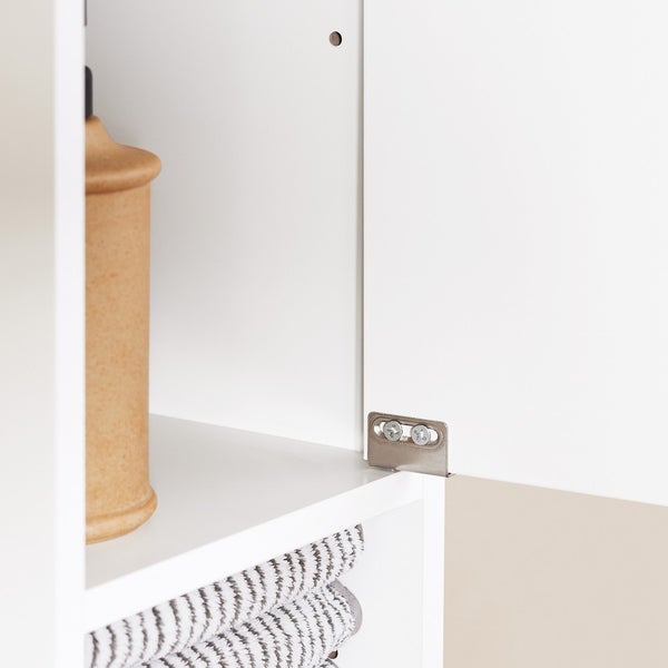 Innenansicht eines weißen Badezimmerschranks mit Handtüchern und Dekoration