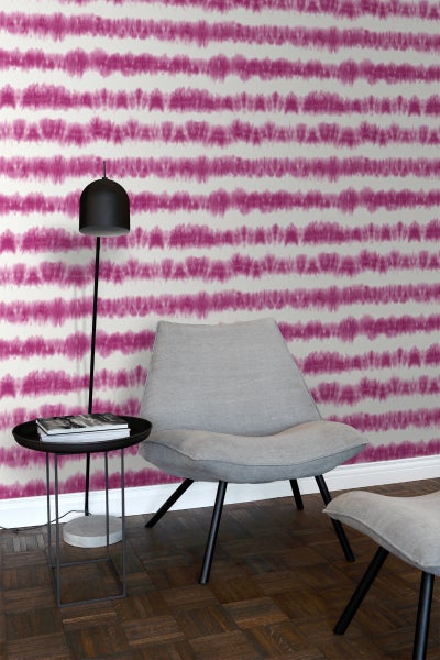 Raumansicht mit gemusterter Tapete, Sessel und Stehlampe.
