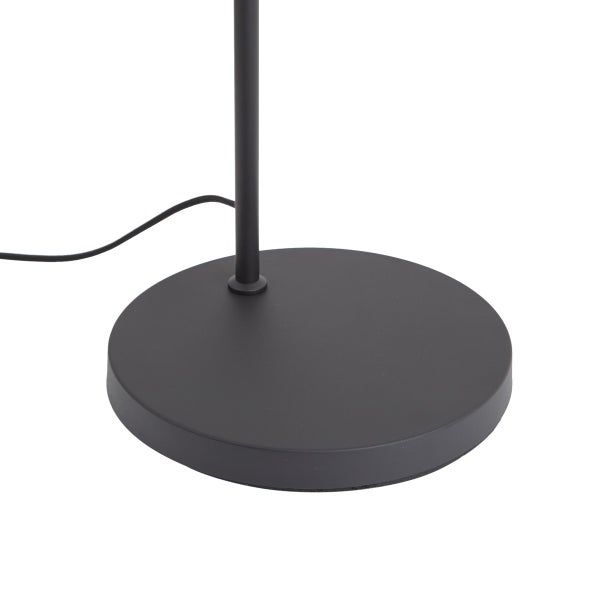 Schwarzer kreisförmiger Standfuß einer Stehlampe aus Metall mit einem schmalen Ständer und einem schwarzen Stromkabel.
