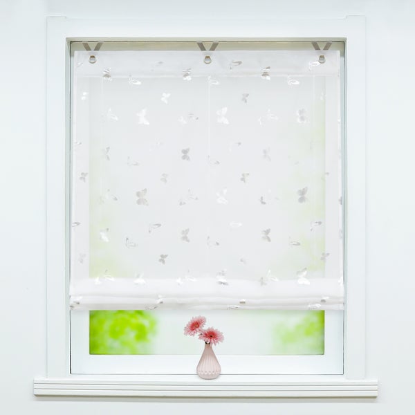 Fenster mit Faltrollo und Schmetterlingsmuster sowie einer Vase mit Blumen auf dem Fensterbrett.