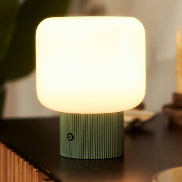 Moderne LED Tischleuchte mit grünem geriffeltem Sockel und weißem leuchtendem Schirm auf einer dunklen Oberfläche.