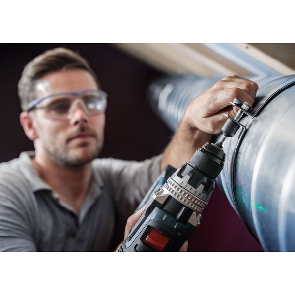 Ein Mann befestigt mit einem Akkuschrauber ein Lüftungsrohr.