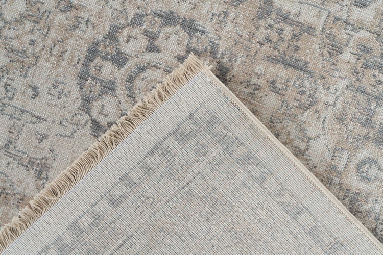 Nahaufnahme eines Teppichs mit Vintage-Muster, Fransen und sichtbarer gewebter Rückseite.