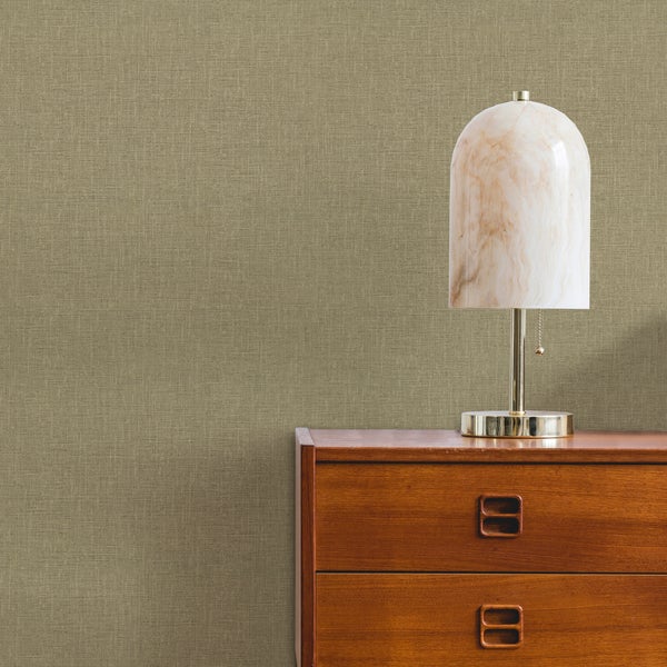 Vliestapete mit feiner Leinenstruktur an einer Wand hinter einer Holzkommode mit einer Tischlampe.