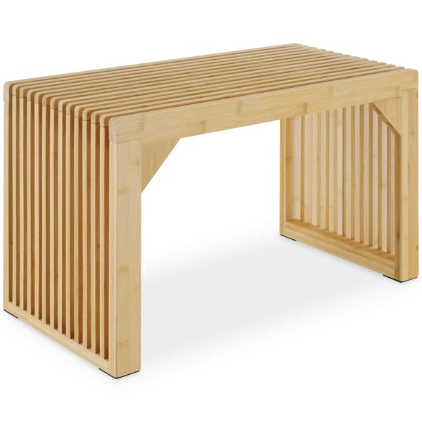 Eine Mutter hilft einem Kind im Bademantel, das auf einer Holzsitzbank mit Lamellendesign in einem hellen Badezimmer sitzt.