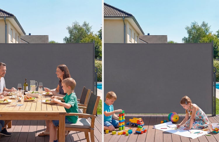Eine graue Seitenmarkise auf einer Holzterrasse bietet Sicht- und Windschutz für eine essende Familie und spielende Kinder.