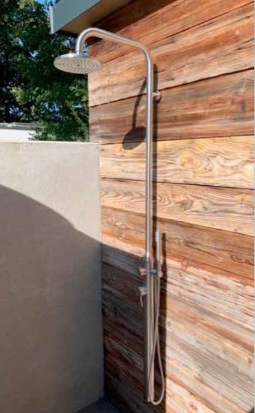 Außendusche aus Edelstahl mit Regenbrause und Handbrause, montiert an einer Holzwand im Garten.