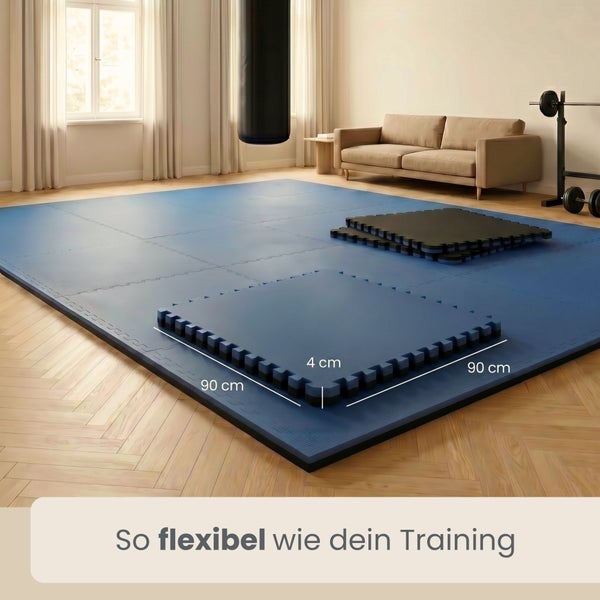 Ineinandergreifende Sportmatten aus Schaumstoff, Maße 90 mal 90 mal 4 Zentimeter, in einem hellen und geräumigen Trainingsraum mit Boxsack.