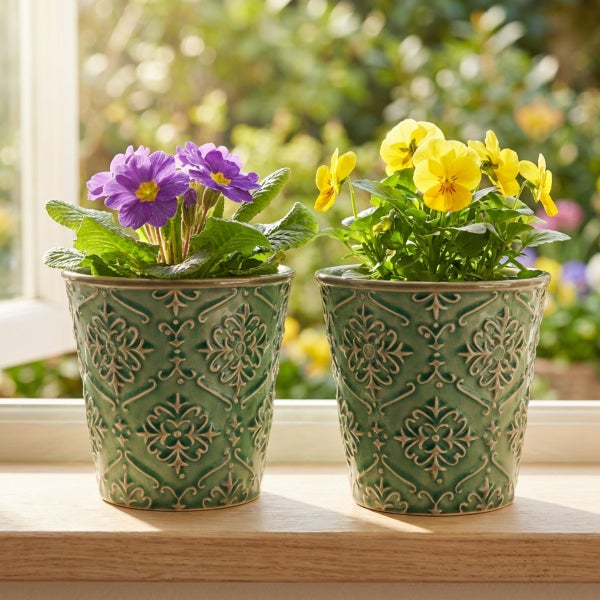 Zwei dekorative Blumentöpfe mit Blumen auf einer Fensterbank