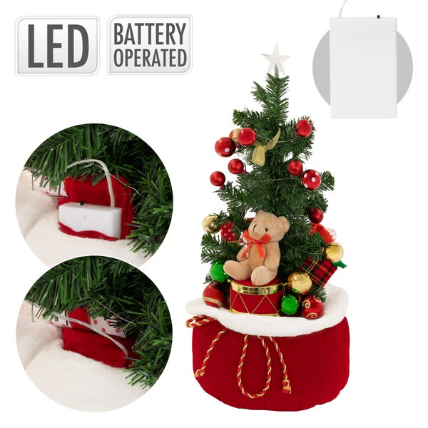 Künstlicher Weihnachtsbaum mit LED Beleuchtung und Dekoration in einem Geschenksack mit Teddybär.
