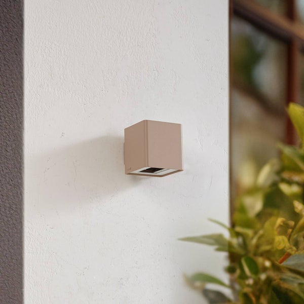 Moderne sandfarbene Außenwandleuchte in Würfelform an einer Fassade, minimalistisches Design für den Außenbereich.