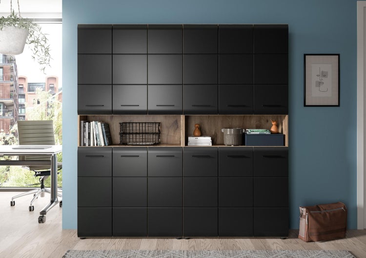 Großer modularer Büroschrank mit schwarzen Fronten, offenen Holzregalen und vielen Türen in einem modernen und hellen Arbeitszimmer.