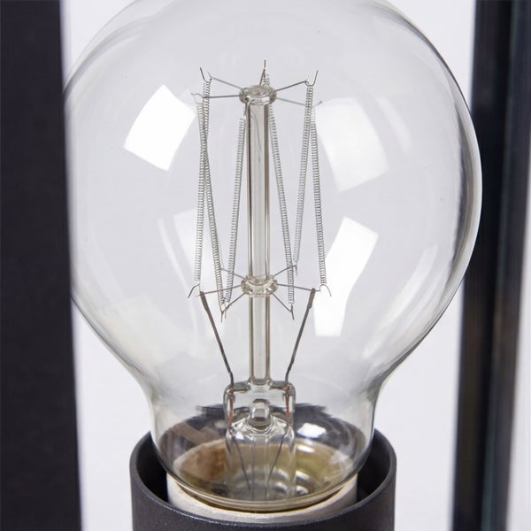 Nahaufnahme einer klaren Glühbirne im Edison-Stil mit sichtbarem Glühfaden in einer dunklen Fassung.