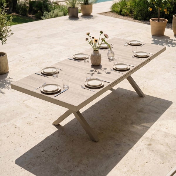 Großer Ausziehtisch mit zehn Gartenstühlen auf einer hellen Steinterrasse am Pool. Modernes Design aus Metall und Holzoptik in einem Garten.