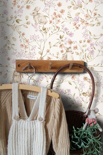 Vliestapete mit Hasen und Blumen im Kinderzimmer mit Holzgarderobe und Strickkleidung.