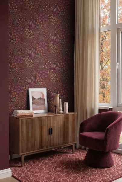 Wohnraum mit Tapete mit botanischem Muster, Sideboard aus Holz, Samtsessel und Fenster mit Vorhang.