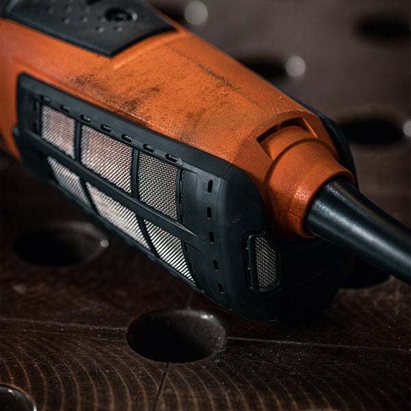 Detailansicht eines orangefarbenen Fugenkratzers mit schwarzem Griff und Metallsieben auf einer dunklen Holzoberfläche.