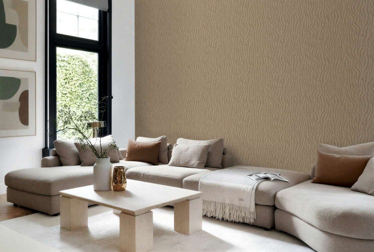 Wohnzimmer mit beigefarbener Tapete mit Wellenmuster hinter einem modernen Sofa und einem quadratischen Couchtisch in einem hellen Raum.