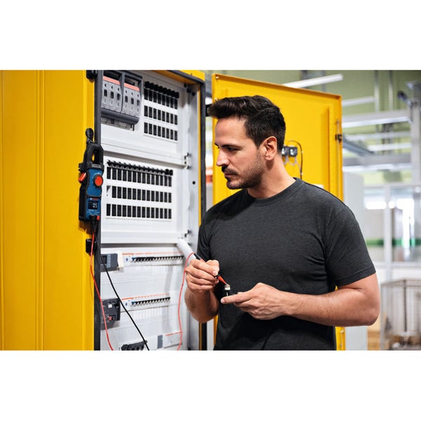 Ein Elektriker überprüft mit einem Multimeter die Spannung in einem Verteilerkasten.